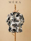 Floral patterned shirt on a hanger with 'Méra' branding against a beige background